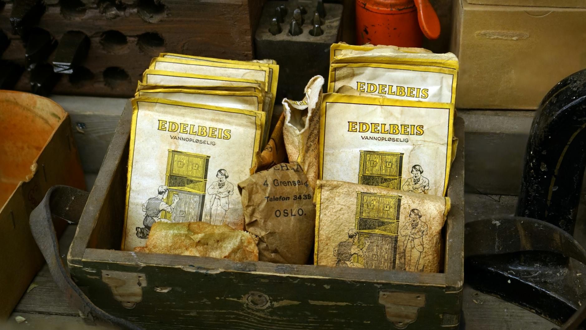 Alte Verpackungen für Holzbeize in einer Holzkiste in einer Werkstatt.